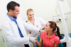 dentist and assistant smiling greeting female patient in dental chair, North York, ON specialist dentistry